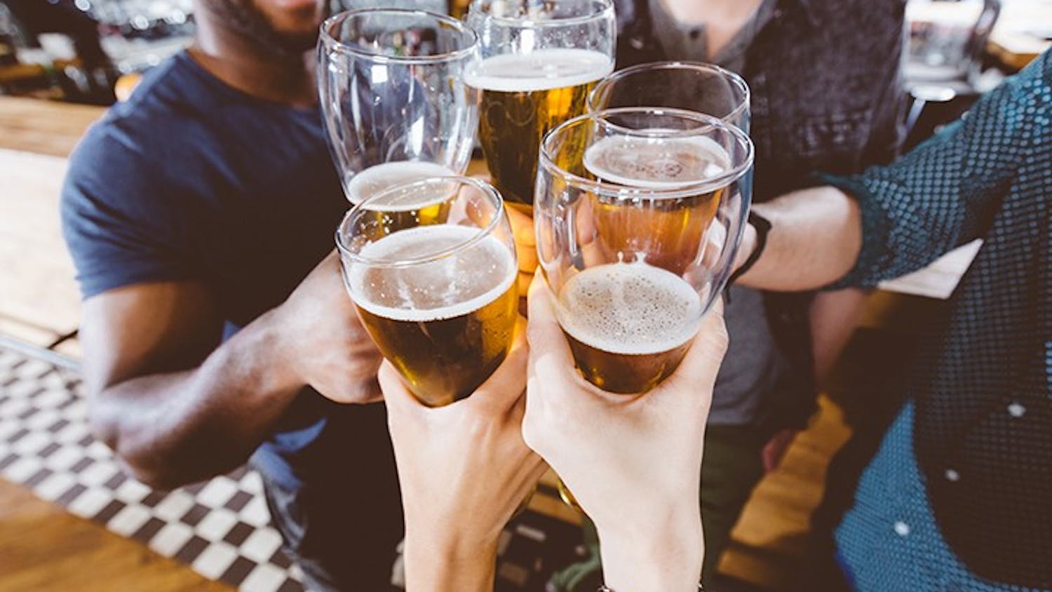  A group of people clink their glasses of beer together.