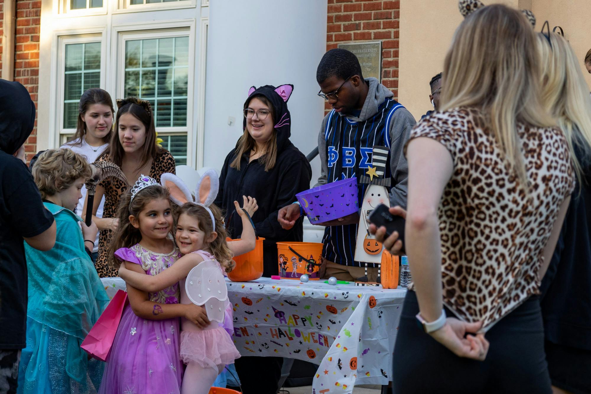 Fraternity and sorority members gather along a decorated table to pass out candy to young trick or treaters on Oct. 25, 2022. USC's Greek Village was home to a trick or treating community event in celebration of Halloween.