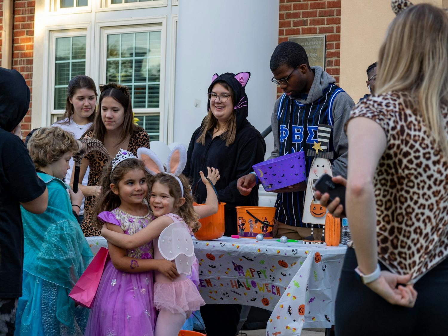Fraternity and sorority members gather along a decorated table to pass out candy to young trick or treaters on Oct. 25, 2022. USC's Greek Village was home to a trick or treating community event in celebration of Halloween.