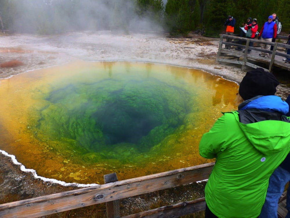 Morning Glory Pool, named in the 1800s for the blue flower it resembled at the time, has turned different colors from new bacteria and algae that have dominated as the pool has cooled because of trash, coins and other debris thrown in over decades. (Brian J. Cantwell/Seattle Times/TNS)