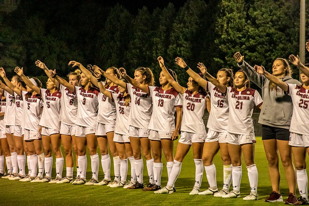 <p>The Gamecocks women's soccer team stands in a line and holds up their “cups” after a game.</p>
