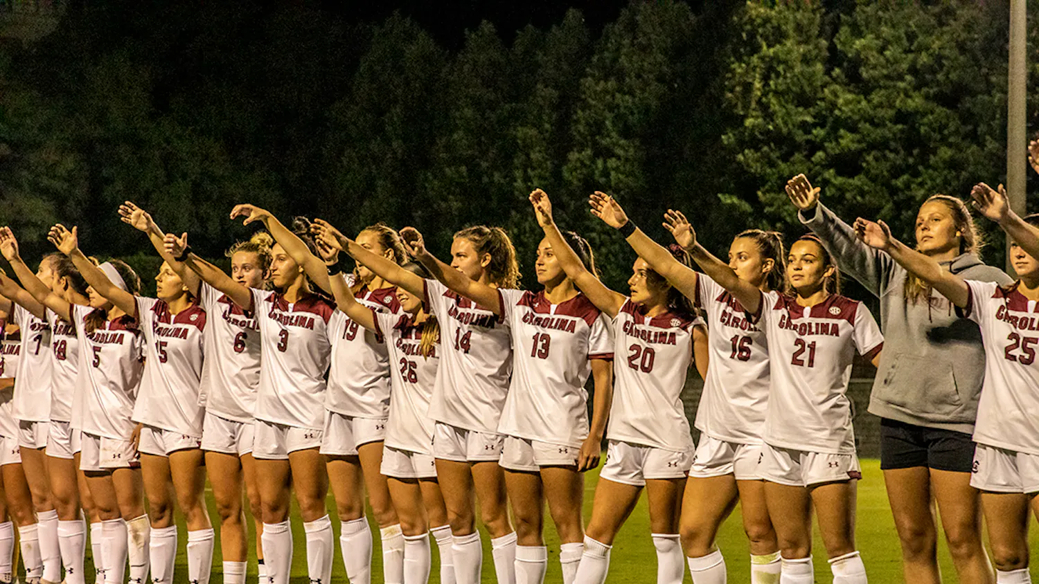 The Gamecocks women's soccer team stands in a line and holds up their “cups” after a game.