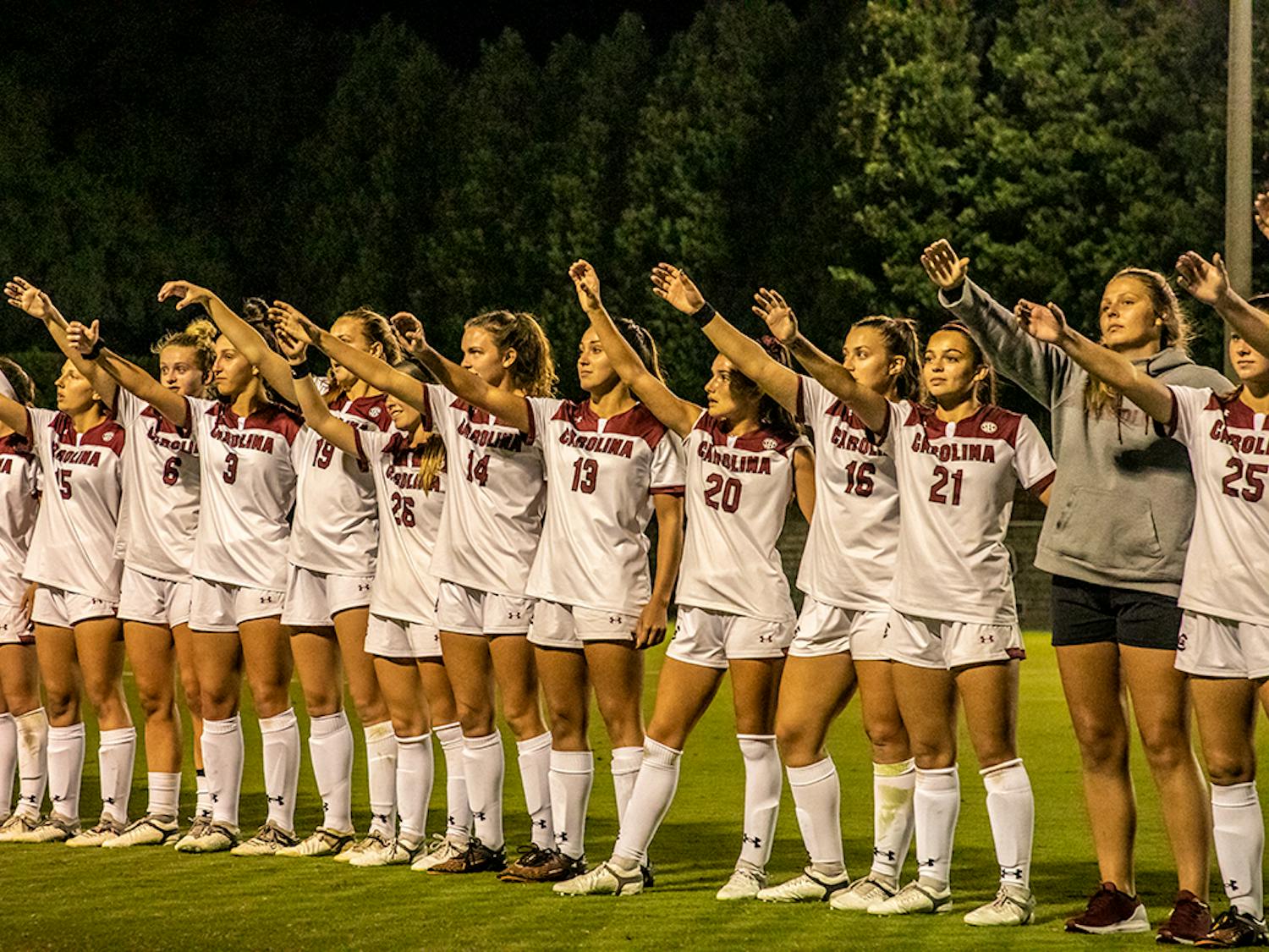 The Gamecocks women's soccer team stands in a line and holds up their “cups” after a game.