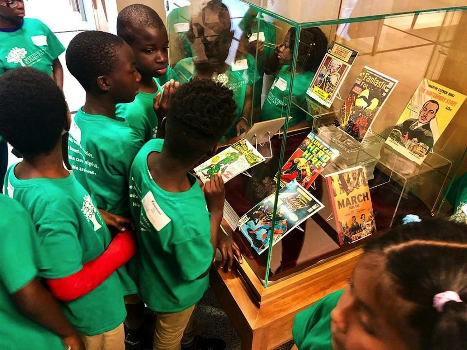 A group of students huddled around a case of books in the Center for Civil Rights History and Research “Justice For All” exhibit in 2019. The center collects and archives historic material and recently received funding from the National Parks Service to continue expanding its exhibits, which are found across multiple buildings on campus.