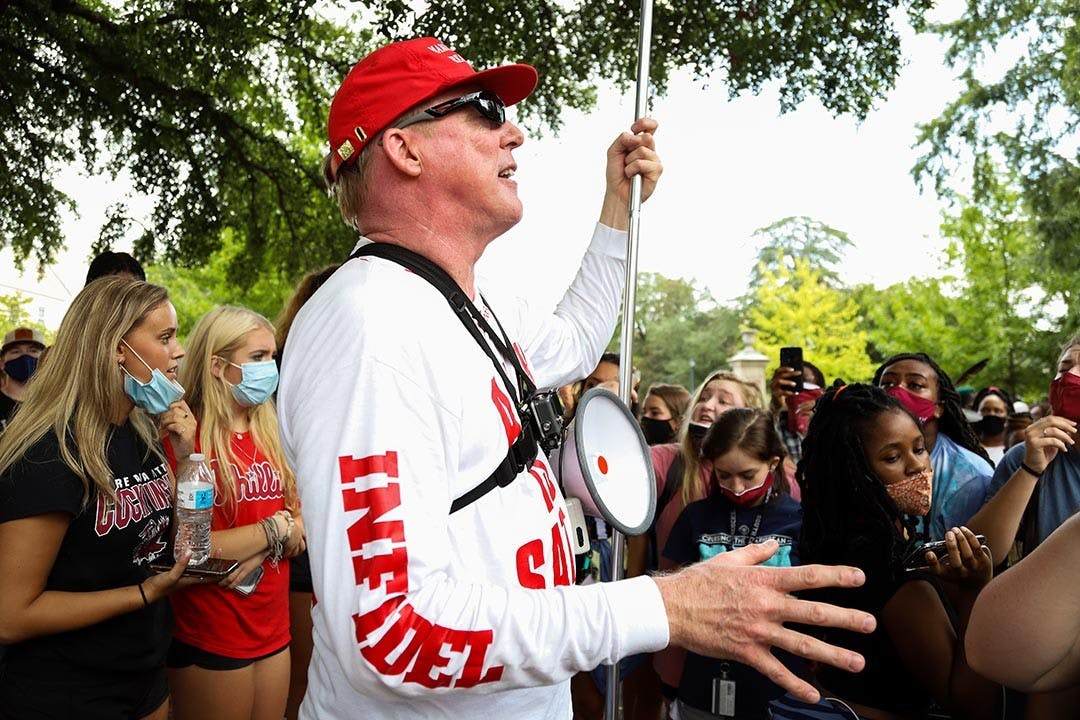 Jim Gilles preaches to the crowd surrounding him on Greene Street Friday afternoon while he holds up his “BLM are Racist Thugs” sign and is decked out in MAGA gear.