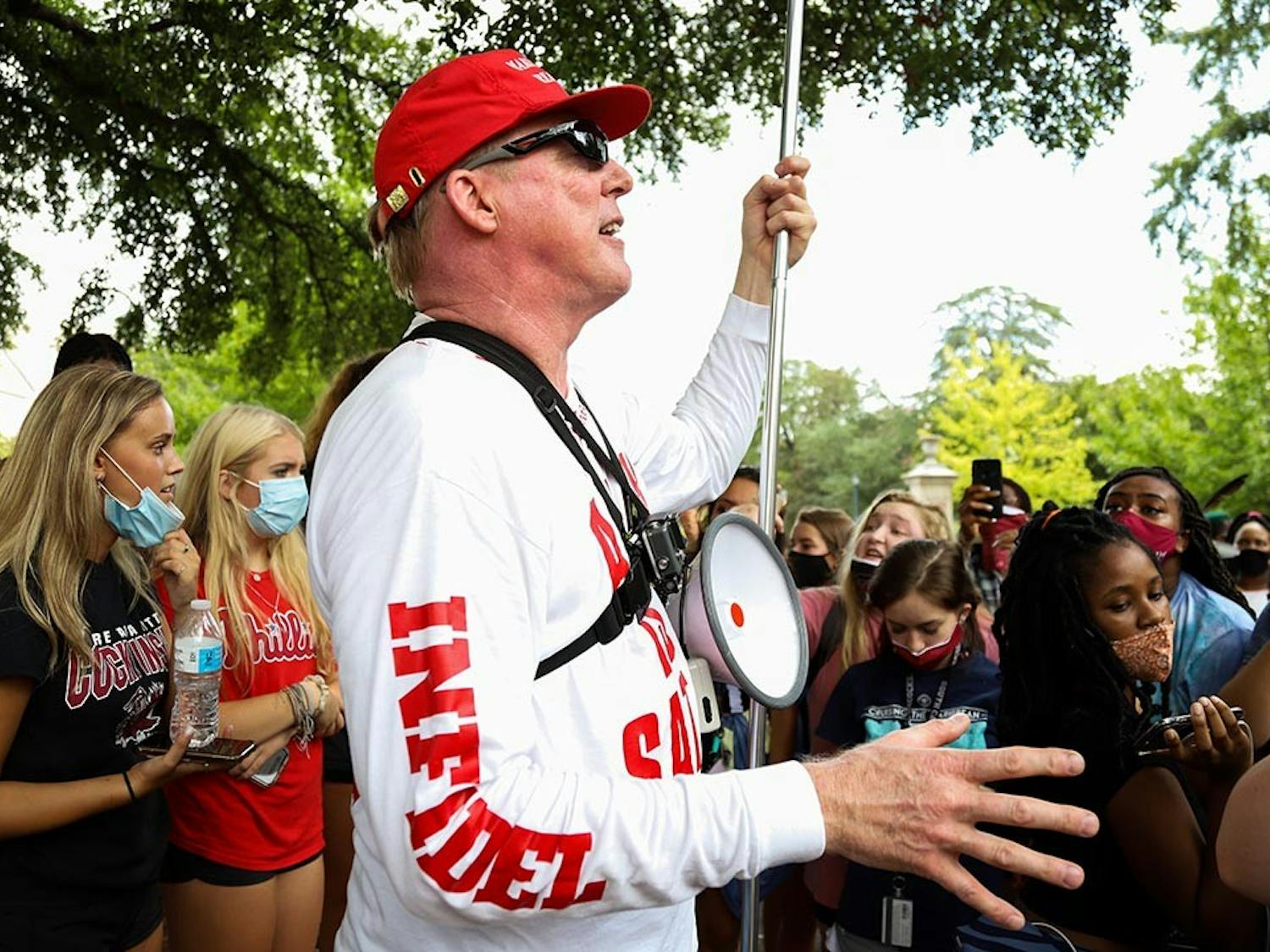 Jim Gilles preaches to the crowd surrounding him on Greene Street Friday afternoon while he holds up his “BLM are Racist Thugs” sign and is decked out in MAGA gear.