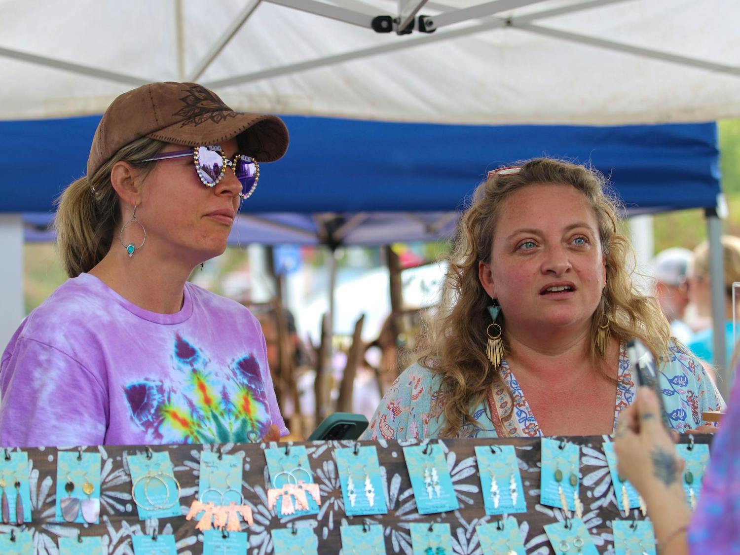 Two vendors discuss merchandise for sale with a customer during JerryFest on Oct. 6, 2024. A variety of people came to JerryFest to sell items, such as necklaces and earrings.