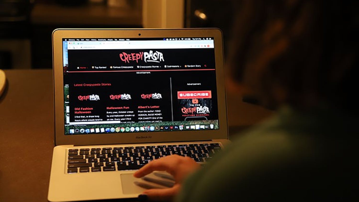  A person at a computer while it is displaying the Creepypasta website. Creepypasta is a horror story website where writers can post stories and receive feedback from their audience.