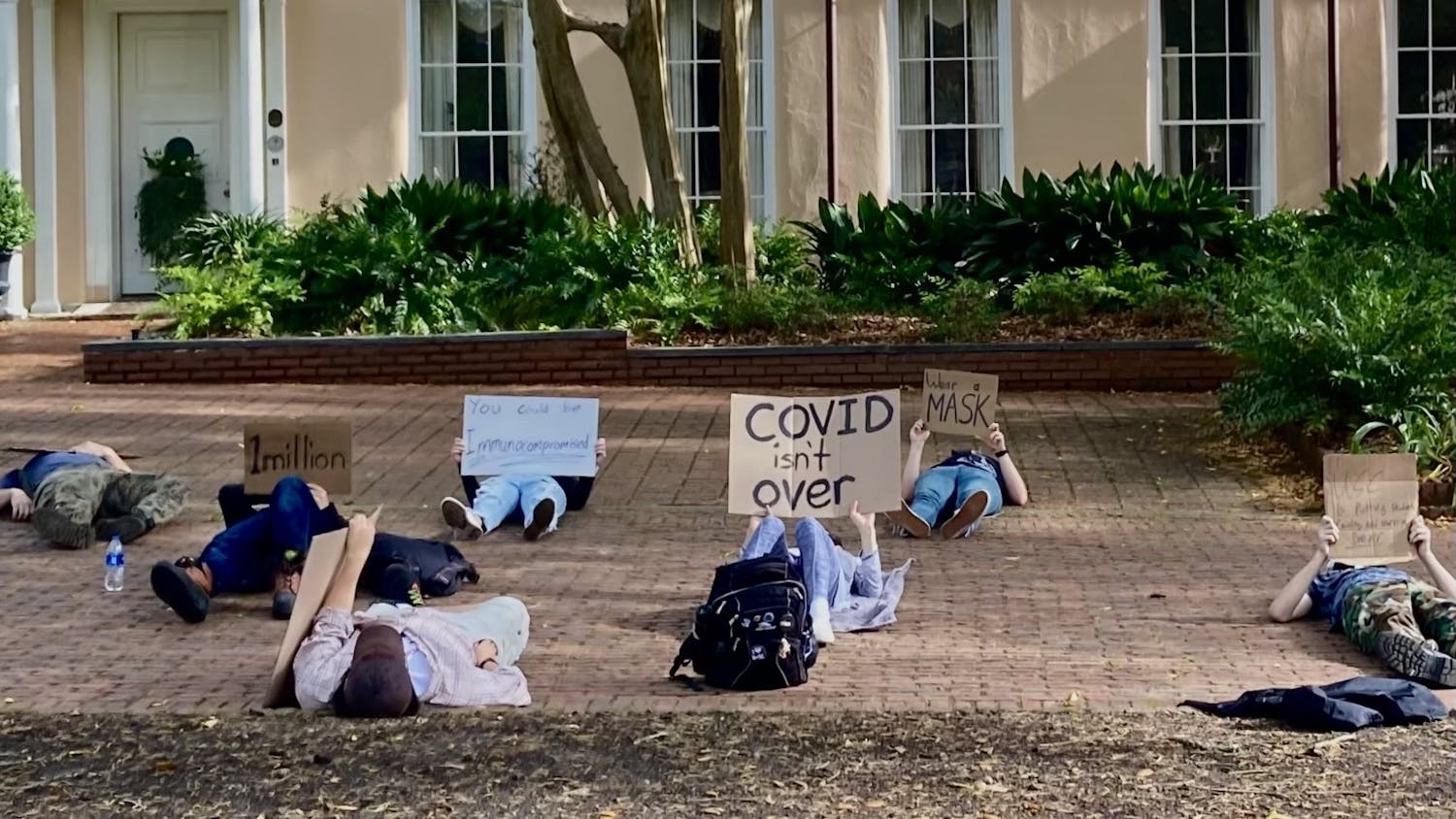 Protestors lay with signs on the Horseshoe at the University of South Carolina on Thursday, March 31, 2022. The protest was held to speak out against the recent removal of UofSC's mask mandate.