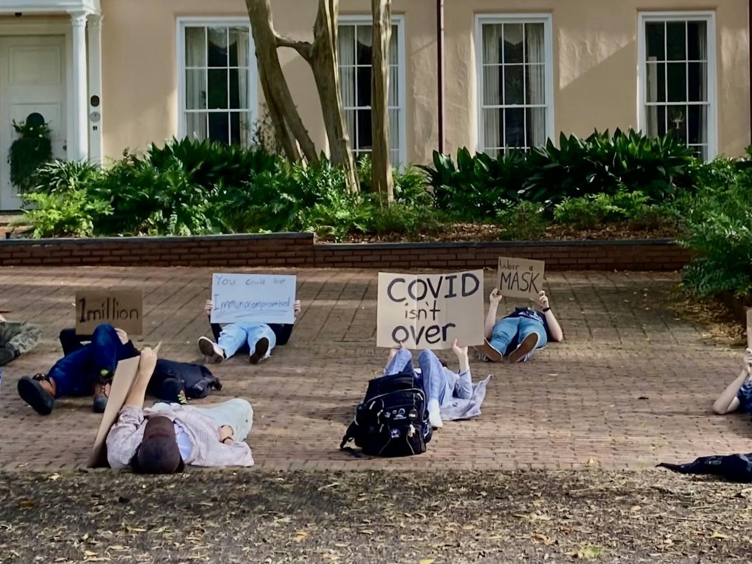 Protestors lay with signs on the Horseshoe at the University of South Carolina on Thursday, March 31, 2022. The protest was held to speak out against the recent removal of UofSC's mask mandate.
