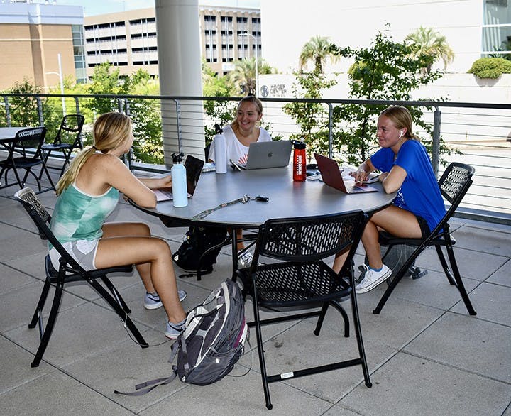 USC students sit outside and work from their laptops.