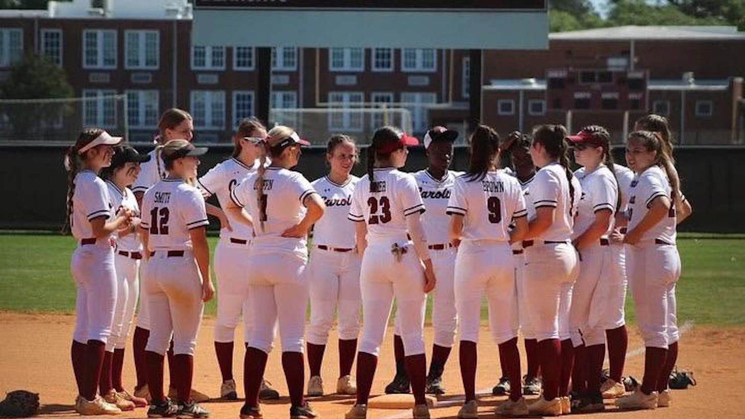 The Carolina Club Softball team gathers in the middle of a field. The team was founded at the University of South Carolina in 2021.