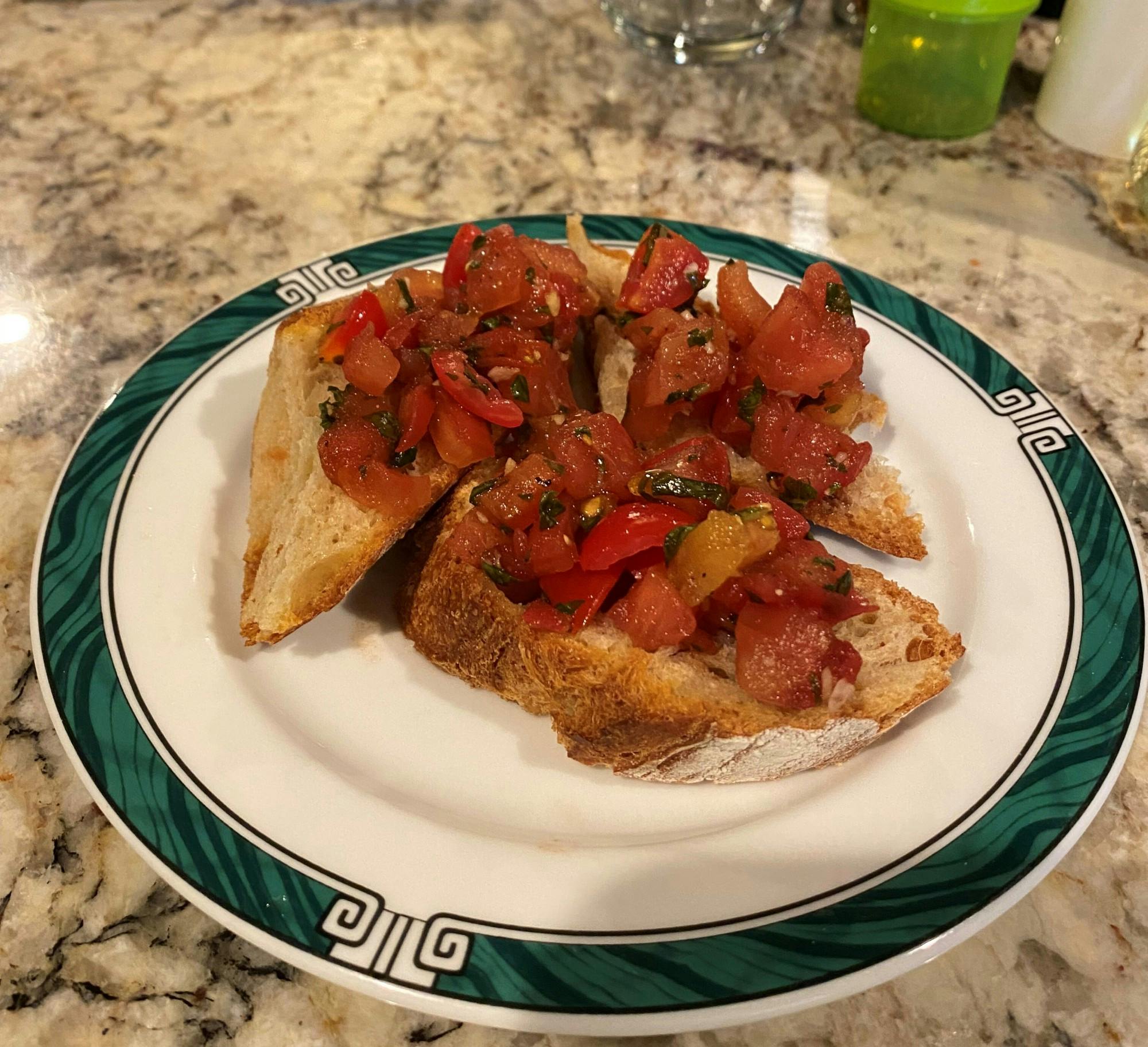 A picture of bruschetta made with fresh tomatoes. The dish is served with toasted bread and a drizzle of olive oil.