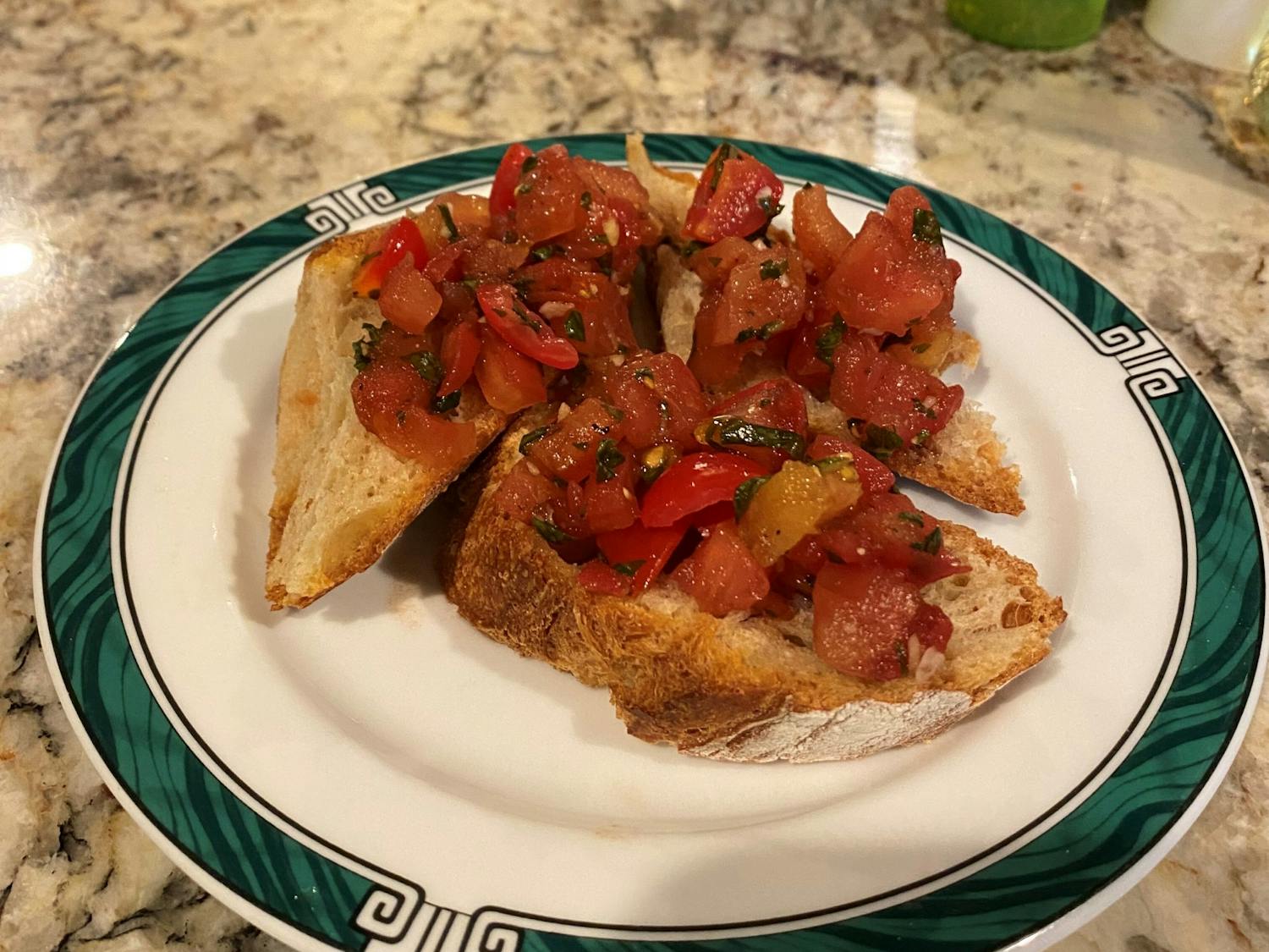 A picture of bruschetta made with fresh tomatoes. The dish is served with toasted bread and a drizzle of olive oil.