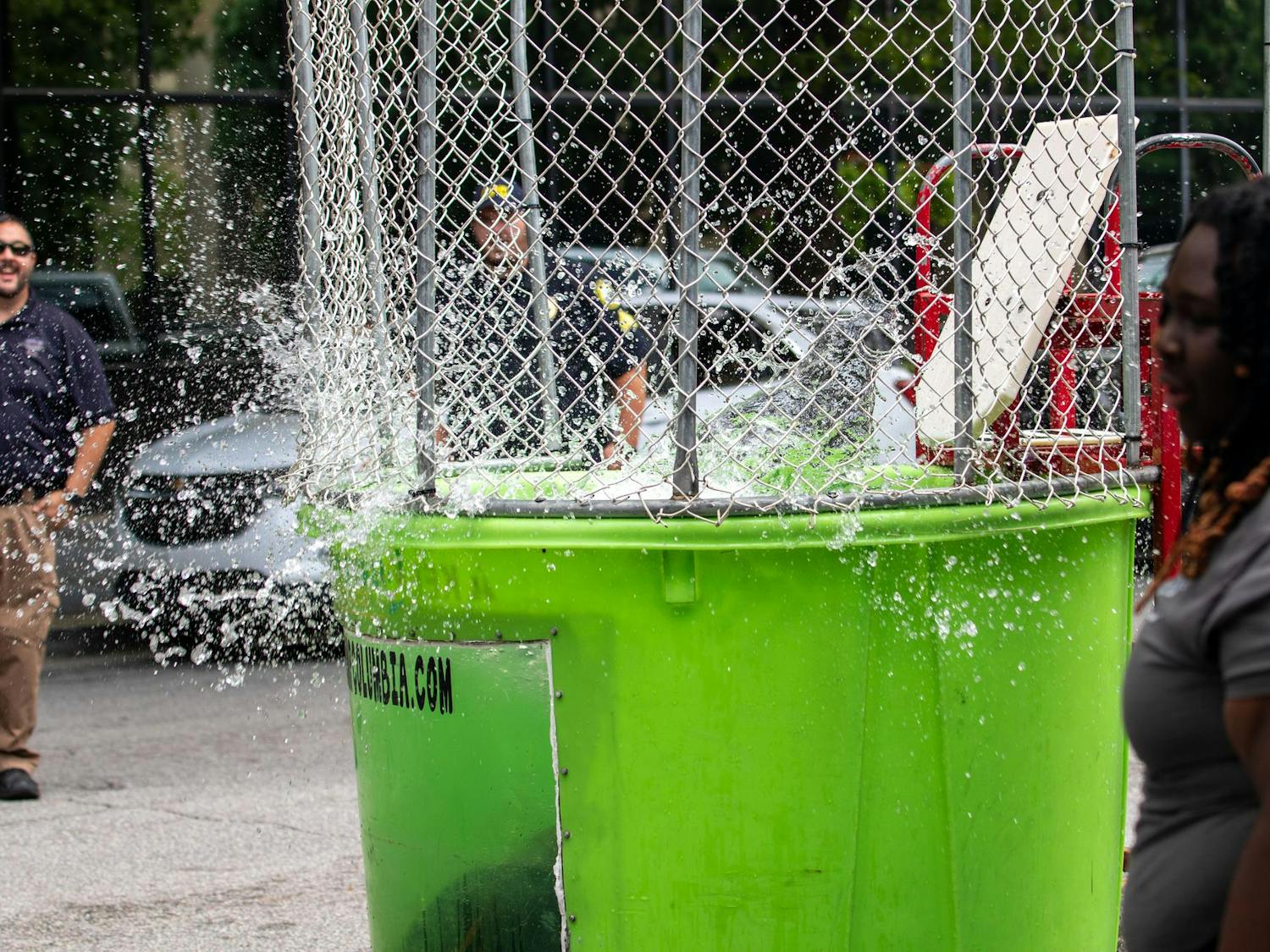 Trevon Fordham, the City of Columbia's Director of Violent Crime Prevention, is dunked in the dunk booth at Soda City Market on July 27, 2024. Fordham was one of many participants whom people could dunk at Sistercare Saturdays to help raise awareness and money for domestic violence.