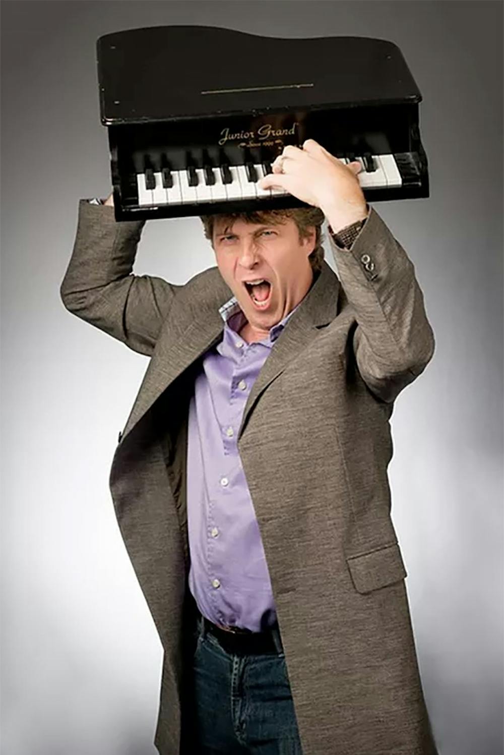 Cutler holds a toy piano over his head for a photoshoot.