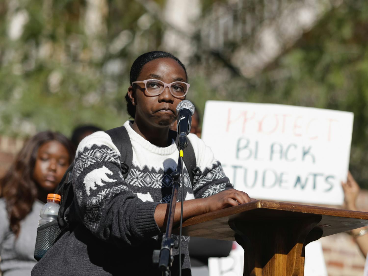 A protester stands in front of the podium with signs in the background on Greene Street on Jan. 20, 2023. The protest was organized by Courtney McClain, a fourth-year broadcast journalism student and the president of the SC NAACP Y&amp;C Division.