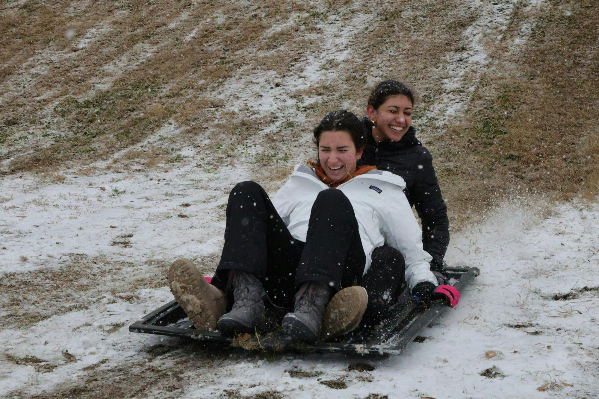 USC students slide down the hill at Athletics Village during snowfall on Jan. 31, 2026. The slope became a popular sledding spot as students used improvised sleds, including dumpster lids, to take advantage of the rare snow.