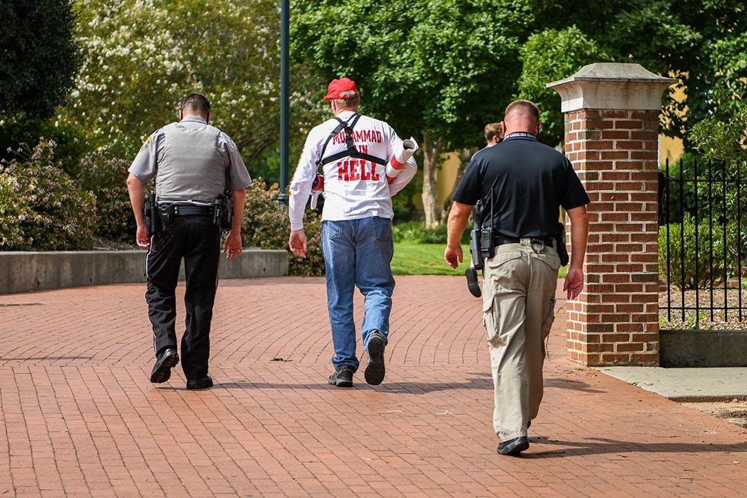 Jim Gilles walks away with a police escort after deciding to leave Greene Street Friday, Aug. 21. The students who were there cheered loudly as he left.