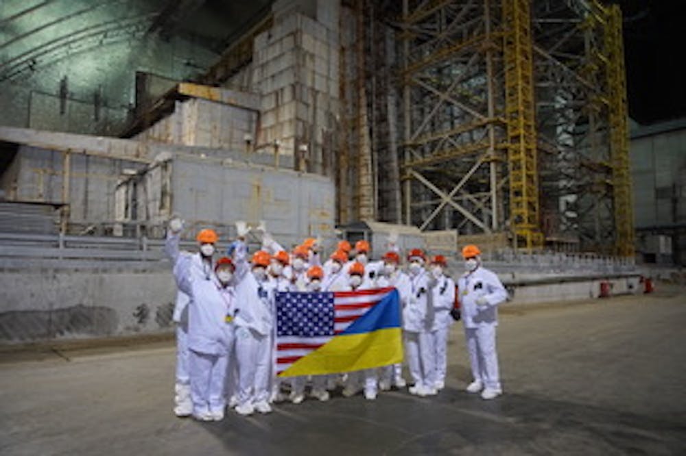 <p>A team of veterinarians, veterinarian technicians and scientists at Chernobyl are in front of the old reactor and its deteriorating sarcophagus. Scientists hold the flags of the United States and Ukraine to represent their works.&nbsp;</p>