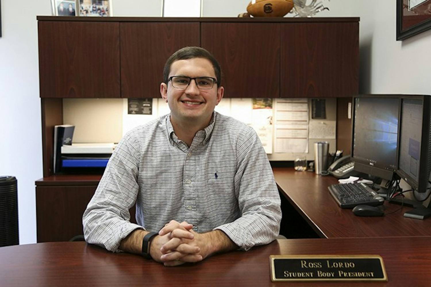 Former Student Body President Ross Lordo sits at his desk while his name plaque is displayed. In his letter, Lordo reflected on athletic achievements, the Cockstock concert and Dance Marathon.