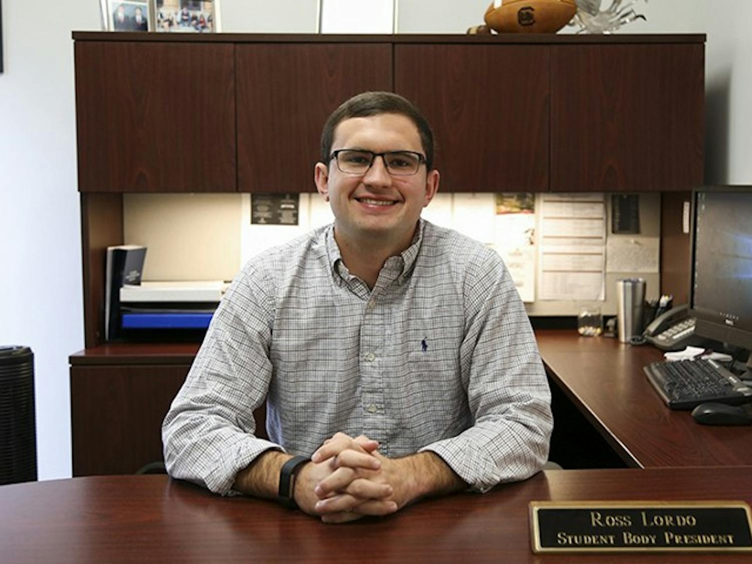Former Student Body President Ross Lordo sits at his desk while his name plaque is displayed. In his letter, Lordo reflected on athletic achievements, the Cockstock concert and Dance Marathon.