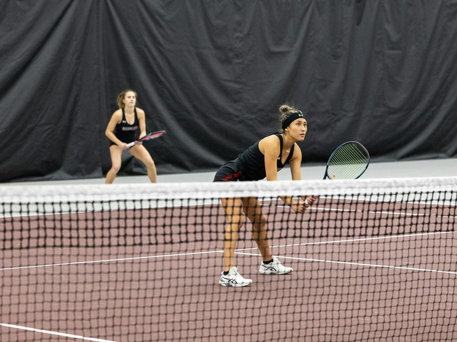 Juniors Misa Malkin and Sarah Hamner take their positions as Coastal Carolina serves the ball. Malkin and Hamner won their doubles competition 6-3.