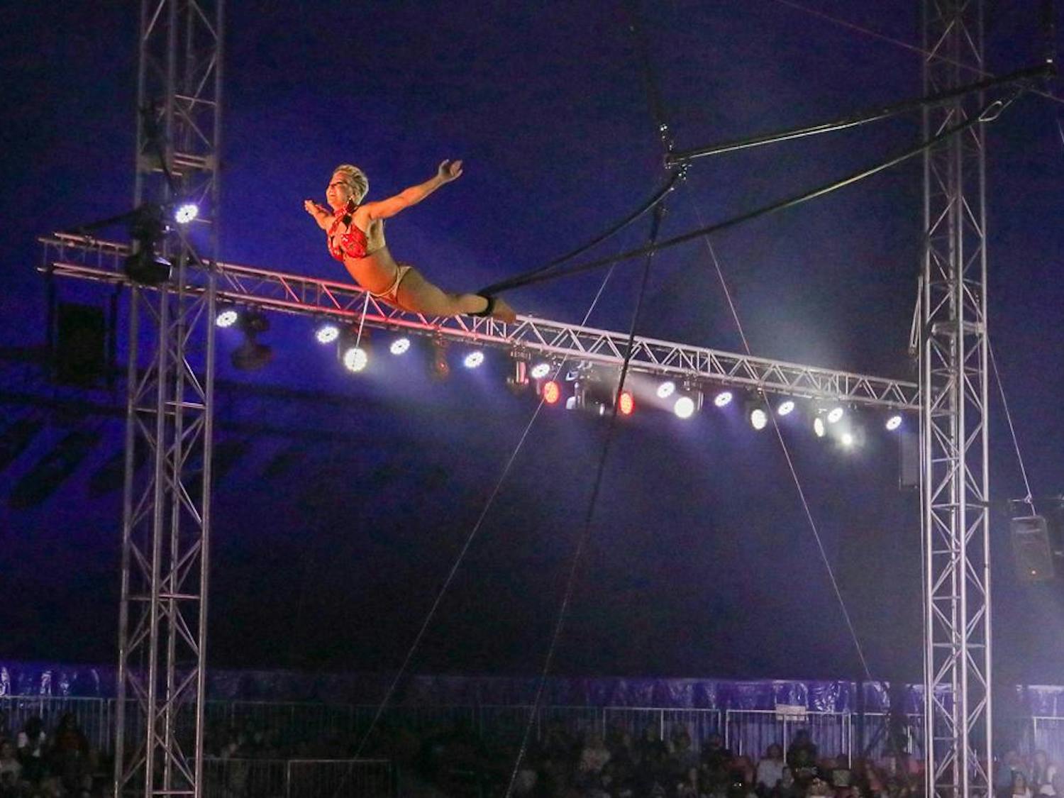 Cloud swing aerialist Susan Vidbel looks at the crowd as she swings back toward the center of the ring during her act at the CIRCUS at the Fair on Oct. 20, 2023. Vidbel's act involves her conducting a series of aerial acrobatics as she swings back and forth above the ring. 