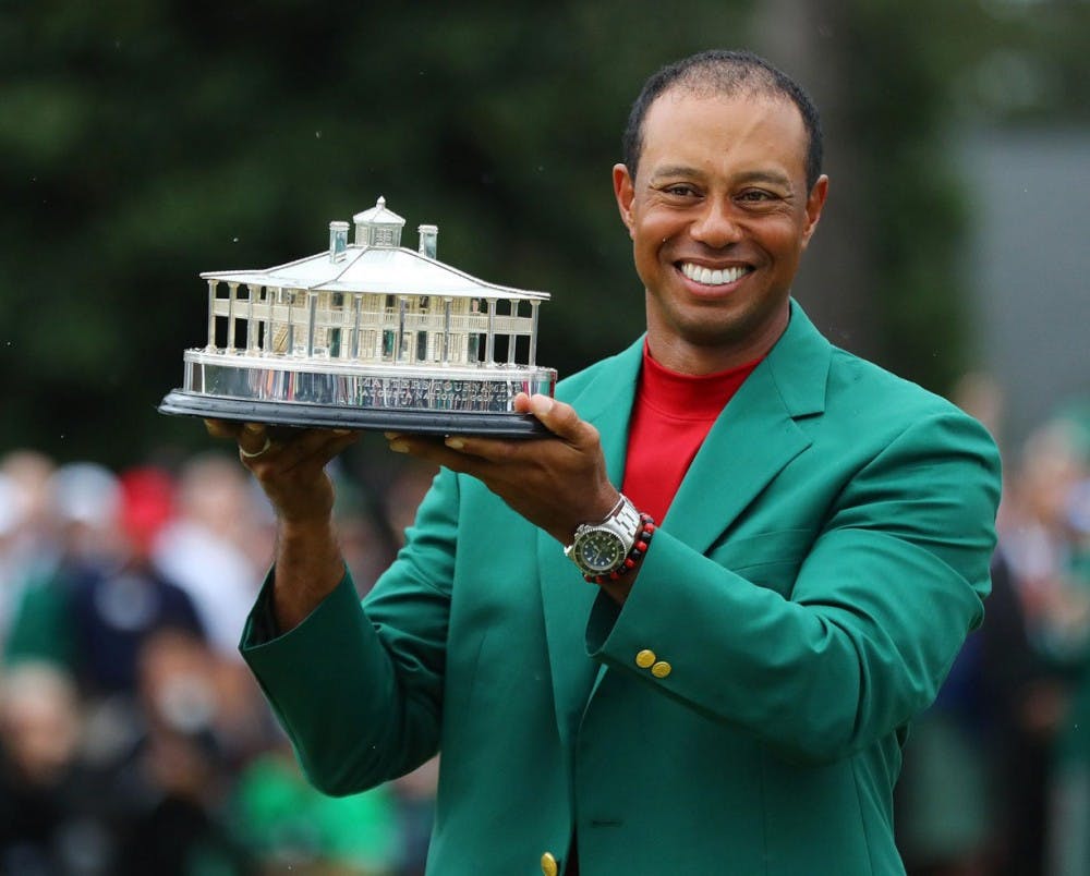 Wearing his new green jacket, Tiger Woods holds the trophy for winning The Masters at Augusta National Golf Club on Sunday. [Atlanta Journal-Constitution via TNS / Curtis Compton]