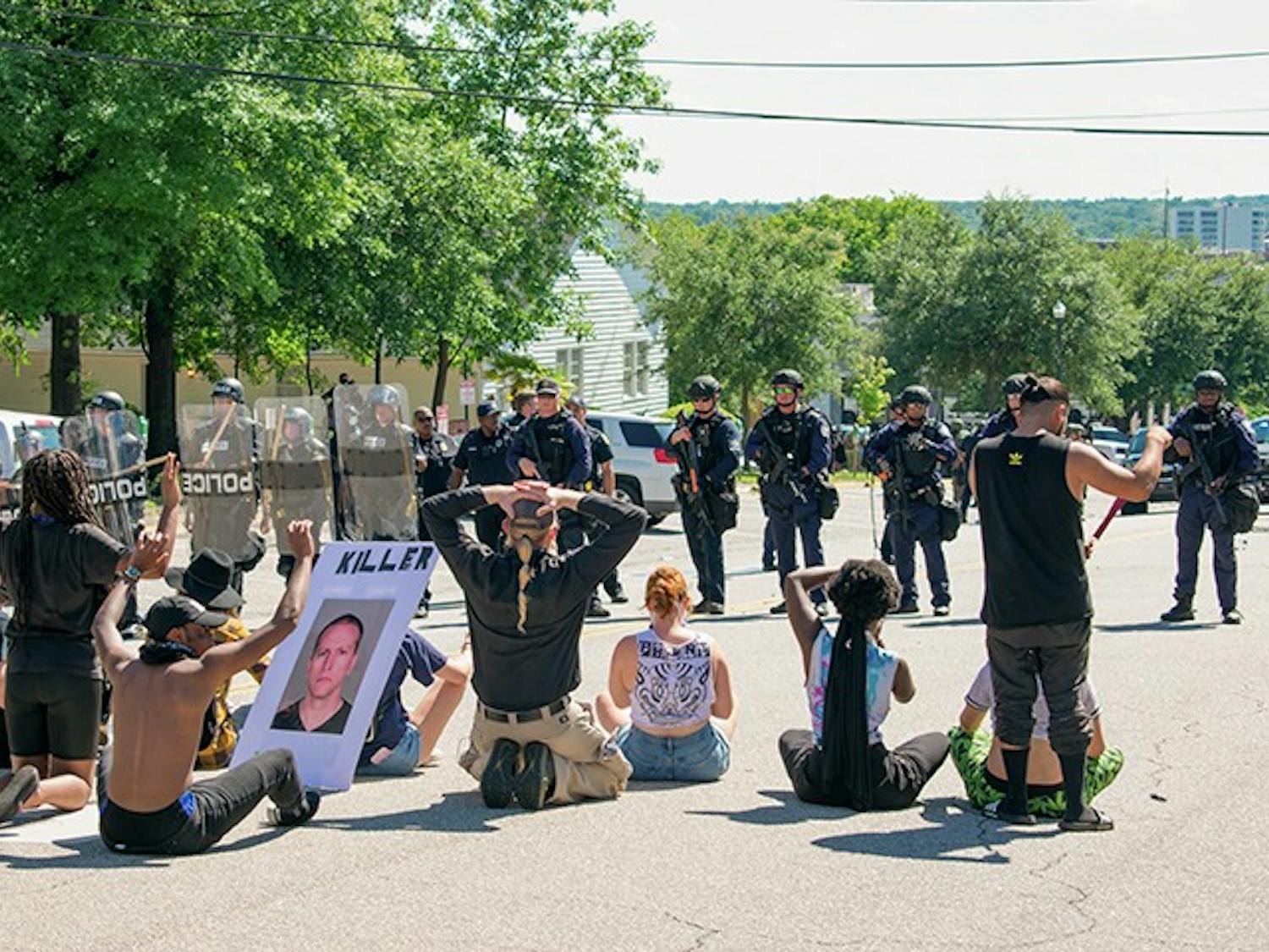 Protesters kneel across from a line of armed police officers in front of the Columbia Municipal Court at the “I Can’t Breathe” protest on May 30.