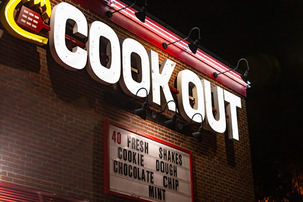 <p>The iconic Cookout logo shines above the front entrance of the restaurant’s Five Points location. The fast-food restaurant originated in Greenville, S.C., and is exclusive to the Southeast region of the United States. The chain offers a wide assortment of burgers, entrees, sides and 40 different flavors of milkshakes.</p>