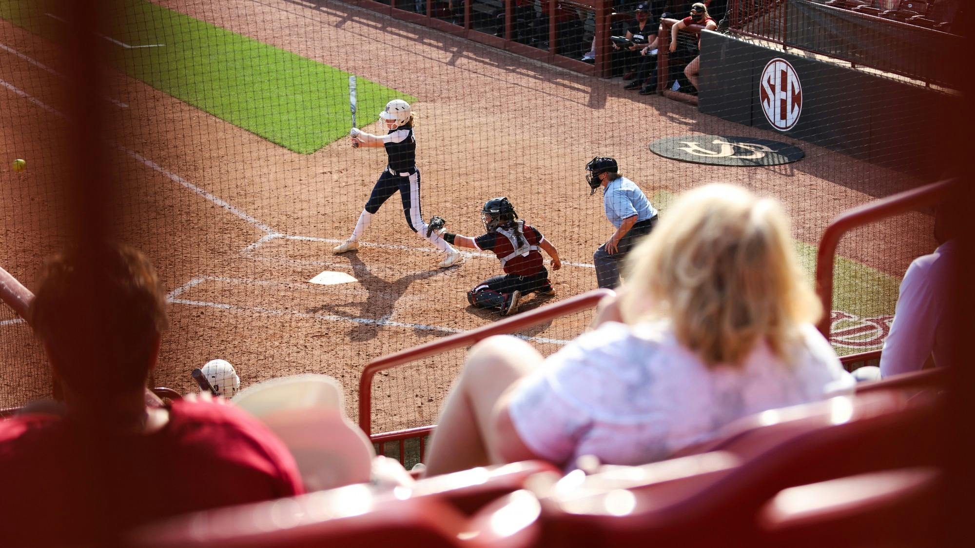 Junior catcher Jordan Fabian prepares to catch the pitch from her teammate while a Charleston Southern player swings at the ball.
