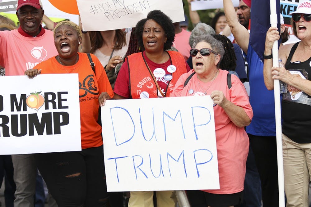 Non-Trump supporters chant and yell while holding protest posters on Oct. 25 before the march began to Benedict College.&nbsp;