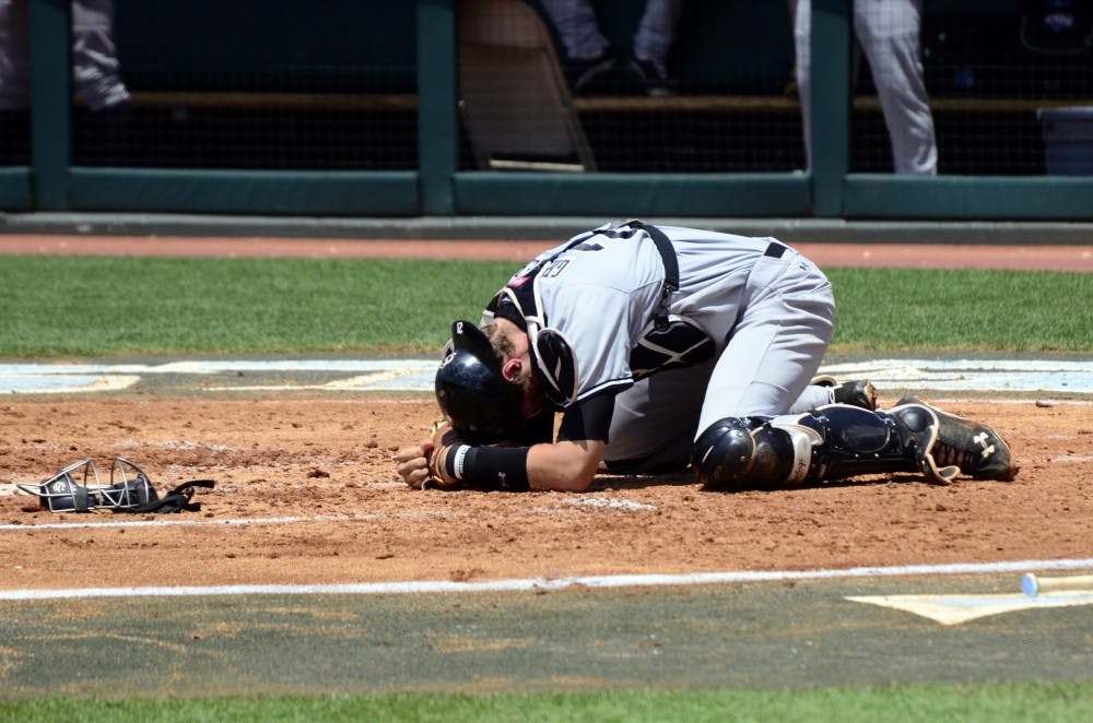 Gamecocks catcher Greiner falls to the ground in pain after being hit in the throat by a ball.