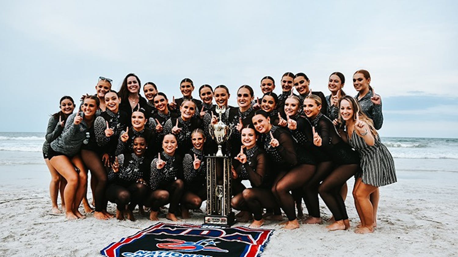 The Carolina Girls dance team posing with the National Championship trophy.
