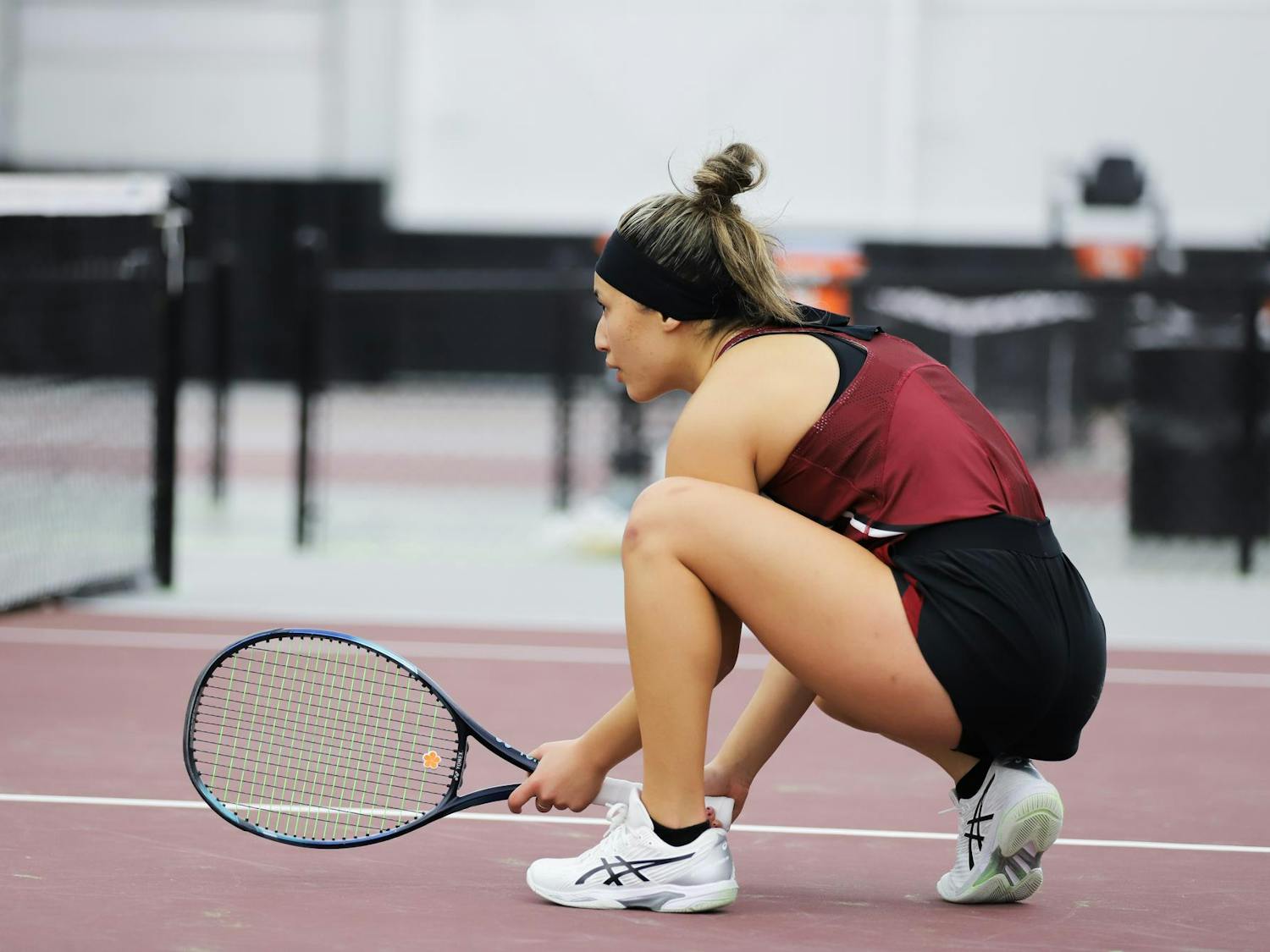 Junior Misa Malkin crouches close to the net, preparing for the serve. Malkin won both her doubles and singles matches against Presbyterian on Jan. 21, 2024, at the Carolina Indoor Tennis Center.&nbsp;