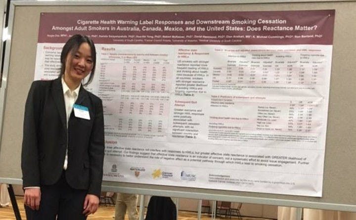 Yoojin Cho stands in front of her research presentation at the Society for Research on Nicotine and Tobacco conference.