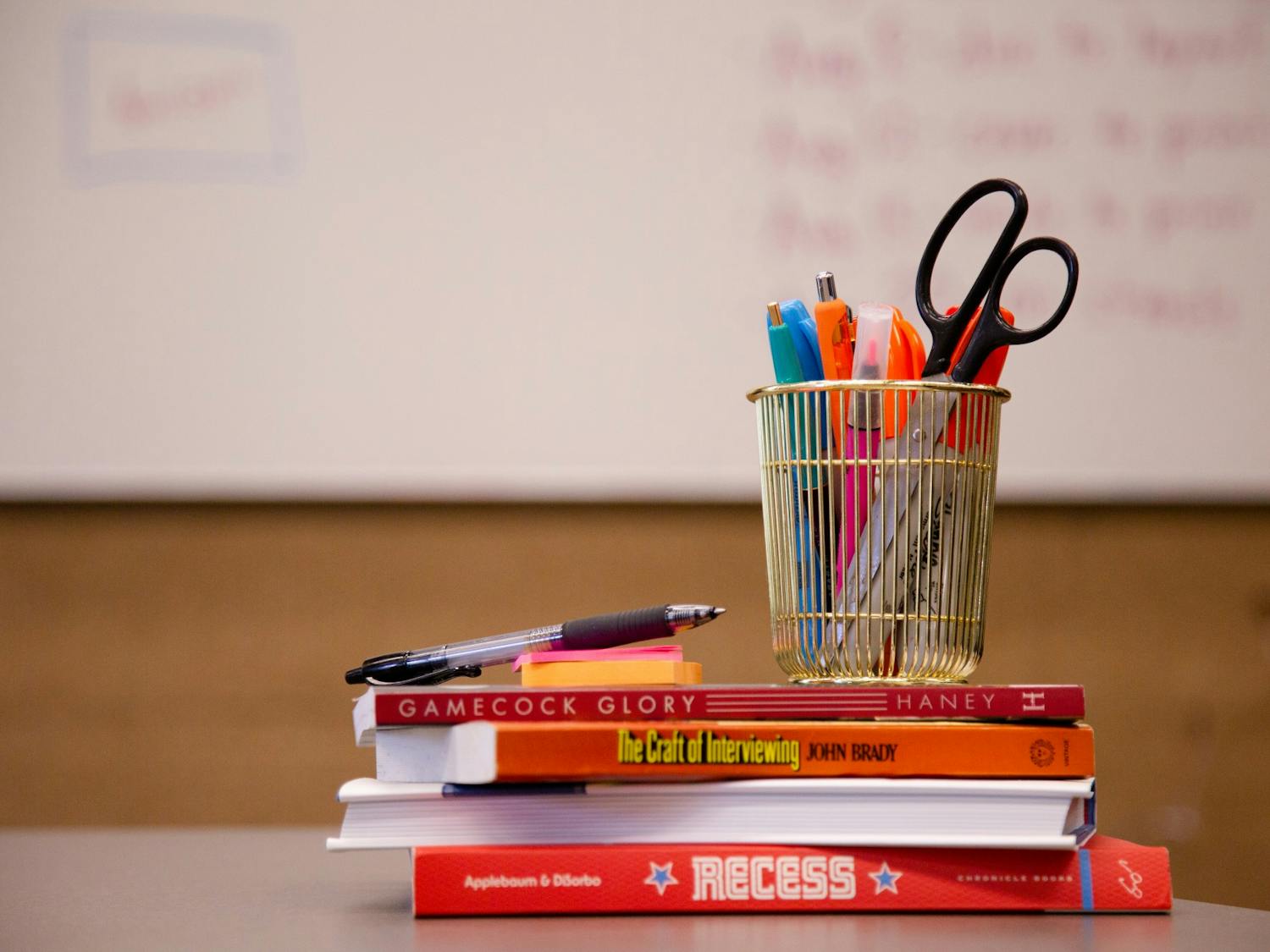A stack of school supplies with a whiteboard in the background taken on July 5, 2022. 