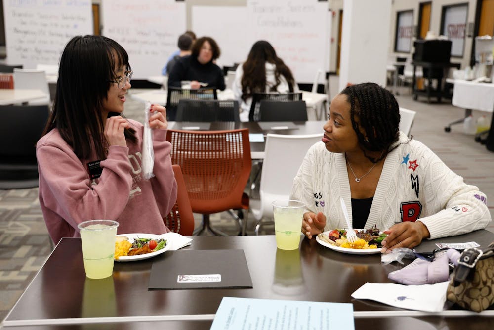 <p>Two students talk together over food at the Transfer Winter Welcome dinner on Jan. 16, 2025. Students could get free food and participate in USC themed trivia while also meeting other transfer students.</p>