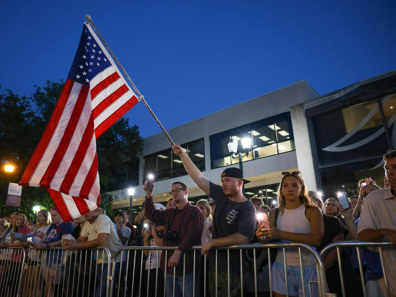 An attendee waves an American flag as the crowd gathers for a vigil honoring Charlie Kirk on Greene Street on Sept. 15, 2025. The USC chapter of Turning Point USA hosted the event and opened it to the community.