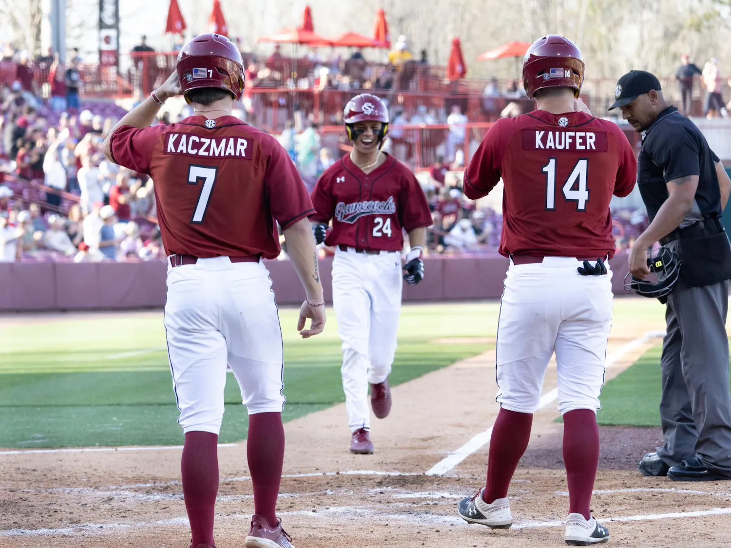 Two University of South Carolina players await their teammate crossing home plate after also scoring a run during their matchup against Morehead State at Founders Park on March 8, 2025. The Gamecocks won 16-11.