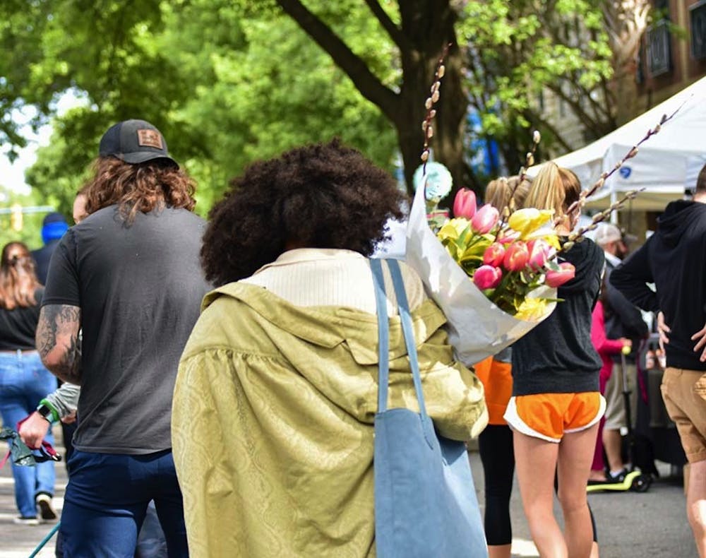 <p>A woman walking with a bouquet of tulips down Main Street through Soda City Market. Soda City is a marketplace where around 150 vendors and artists create a diverse and lively experience for the thousands who attend.</p>