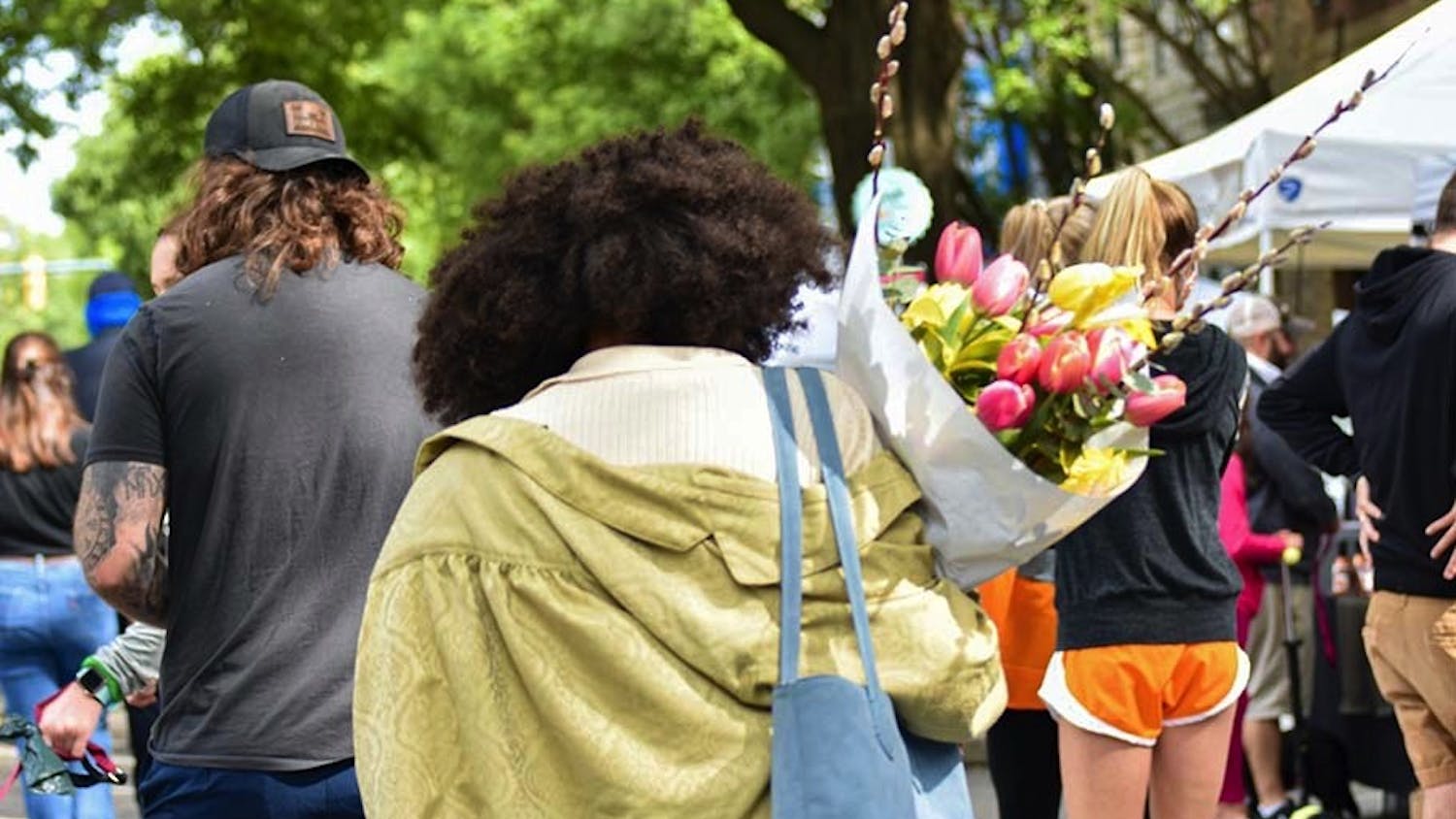 A woman walking with a bouquet of tulips down Main Street through Soda City Market. Soda City is a marketplace where around 150 vendors and artists create a diverse and lively experience for the thousands who attend.