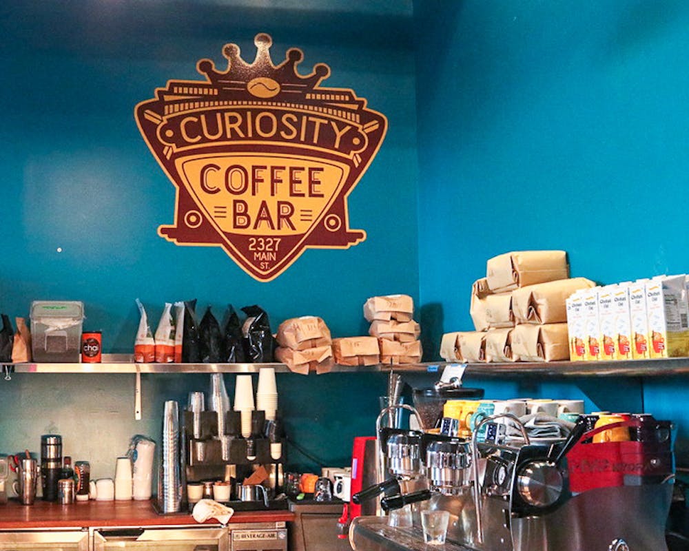 The Curiosity Coffee logo above the coffee bar inside the cafe. Curiosity coffee is located at 2727 Main Street in Columbia, SC.