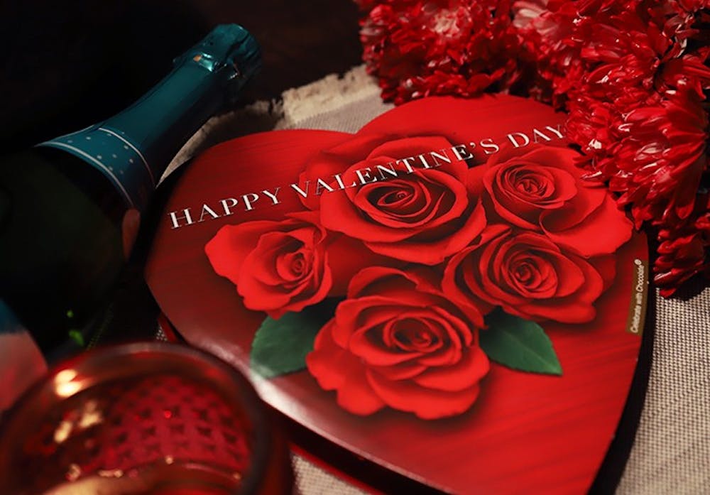 <p>A box of chocolates that say "Happy Valentine's Day" surrounded by other Valentine's Day paraphernalia.</p>