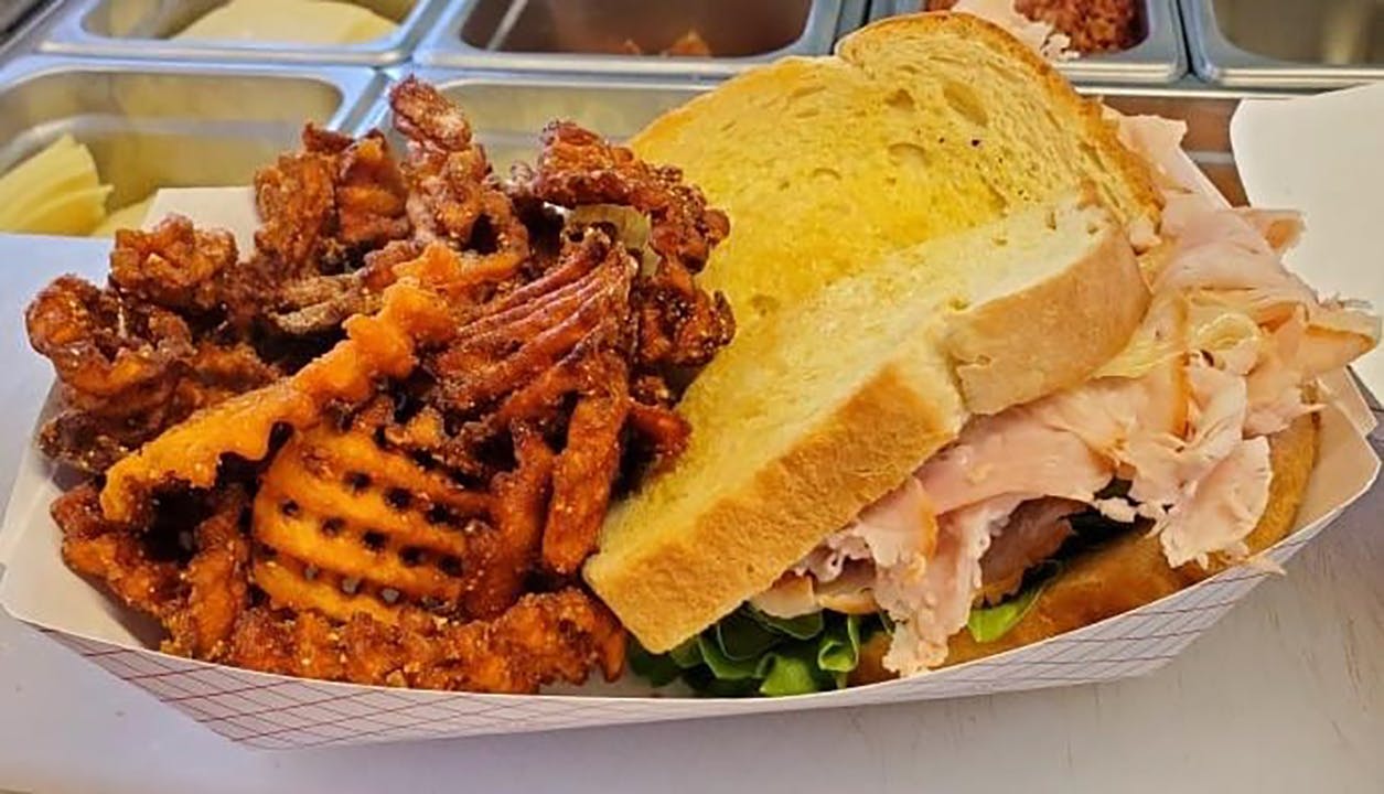 A sandwich from the Hippie Chicks food truck. Hippie Chicks' grilled sandwiches have meat, cheese, lettuce, tomato and onions on sourdough bread with a side of sweet potato fries.&nbsp;