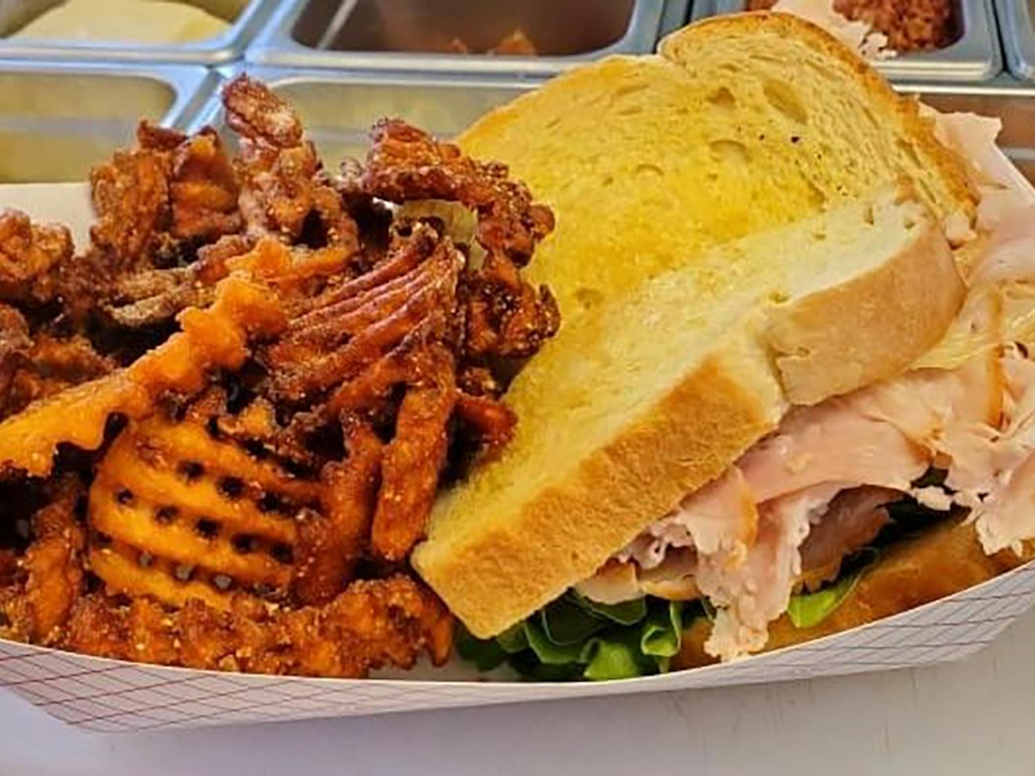 A sandwich from the Hippie Chicks food truck. Hippie Chicks' grilled sandwiches have meat, cheese, lettuce, tomato and onions on sourdough bread with a side of sweet potato fries. 
