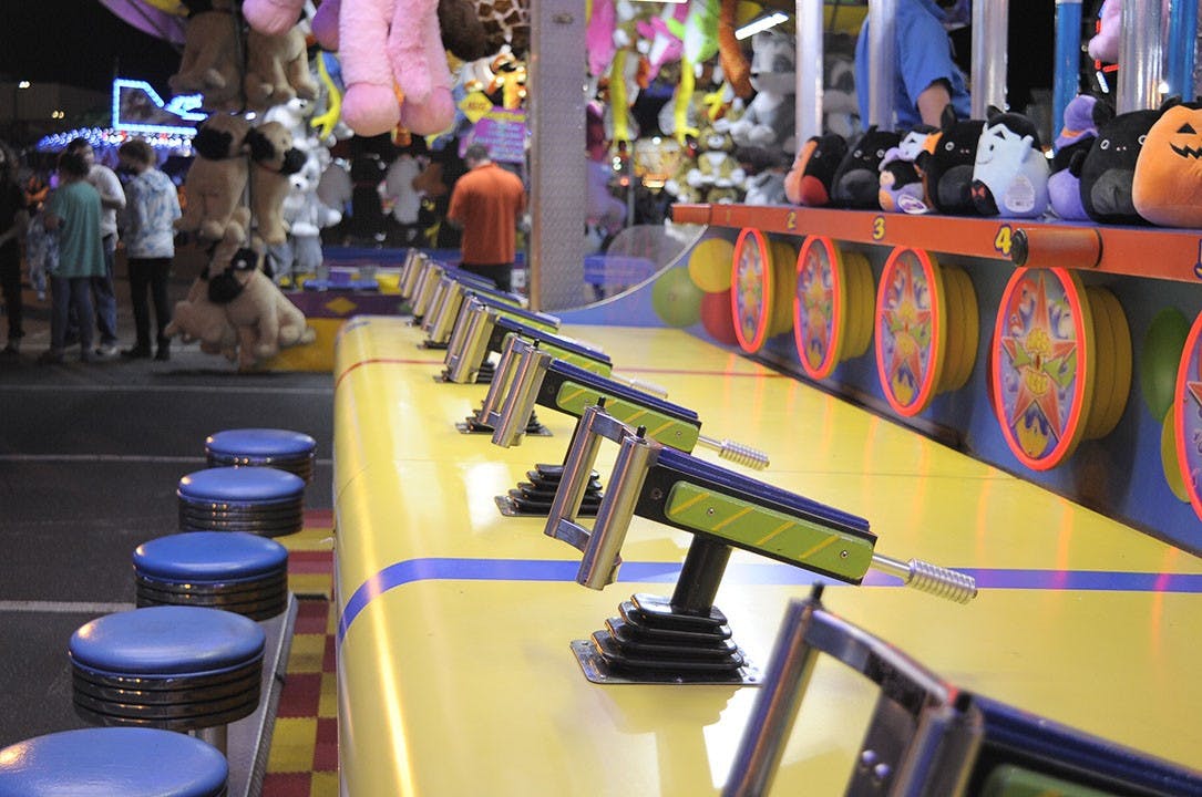 Empty stools await players at a squirt fun game booth at the State Fair.&nbsp;