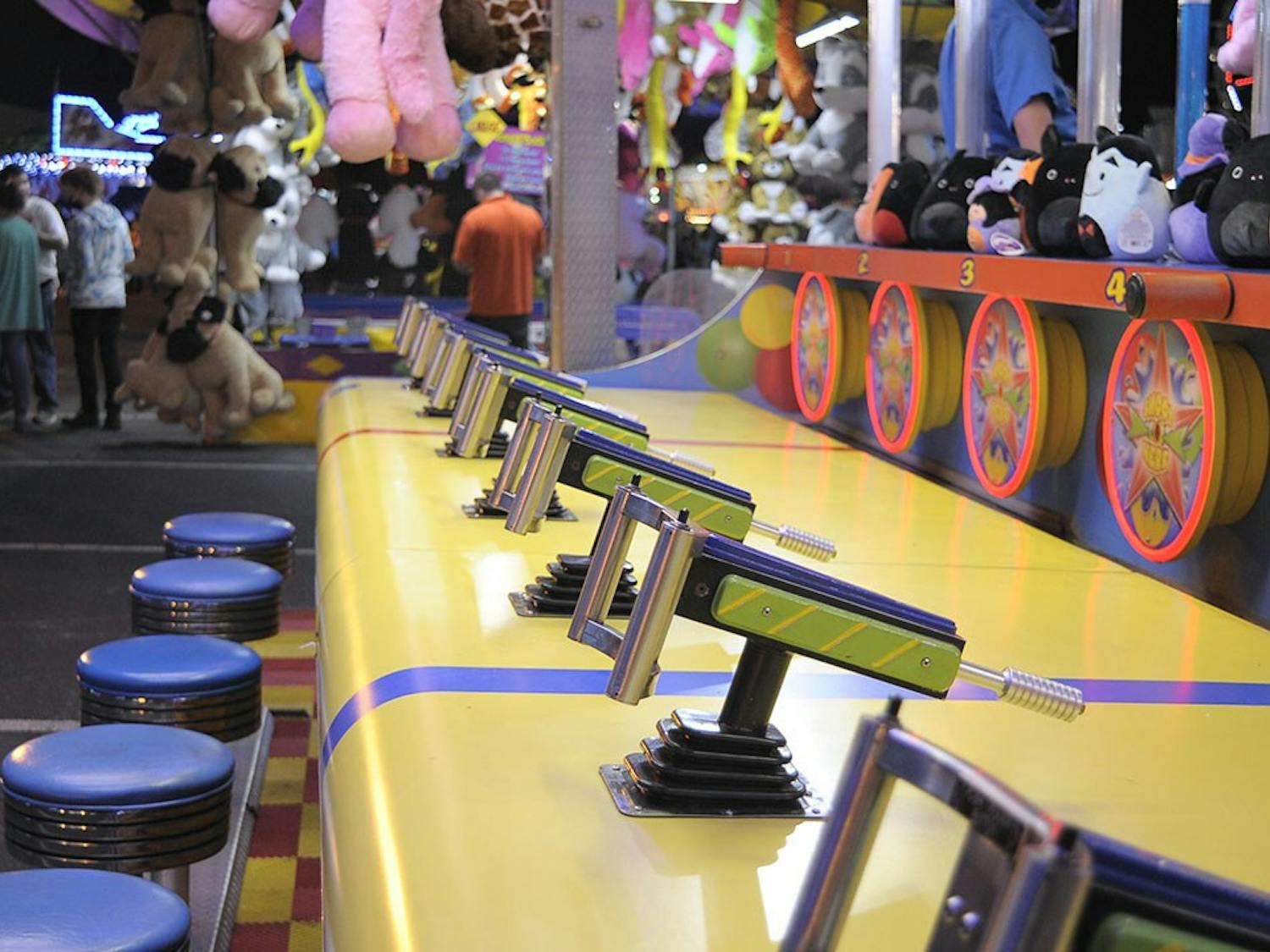 Empty stools await players at a squirt fun game booth at the State Fair.&nbsp;