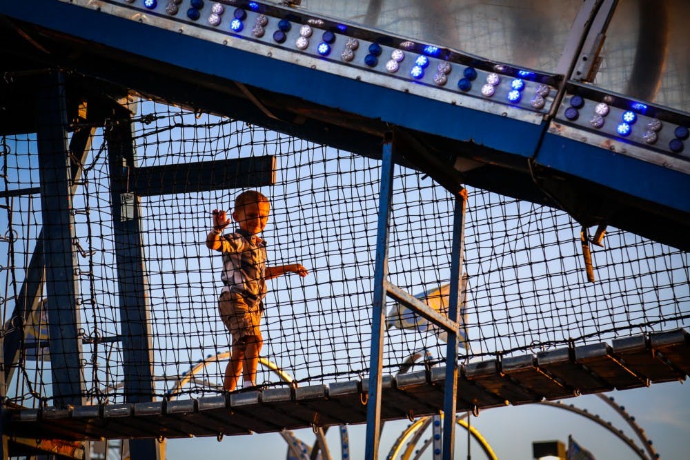 A kid smiles, as his mother tries to take a photo of him.